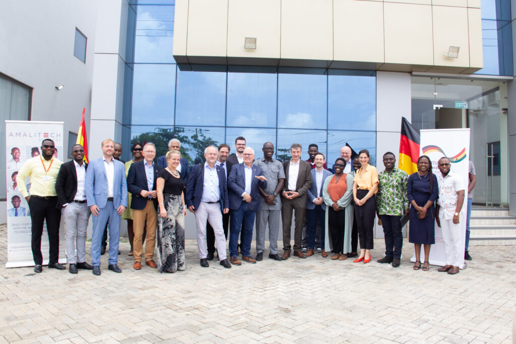 A group of German delegates and senior AmaliTech employees standing together in front of the Accra office, smiling for the camera