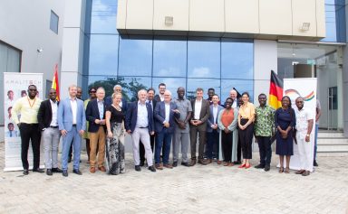 A group of German delegates and senior AmaliTech employees standing together in front of the Accra office, smiling for the camera